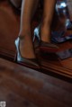 A close up of a woman's shoes on a wooden floor.