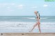 A woman in a bikini walking on the beach.