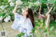 A woman in a blue kimono standing in front of a tree.