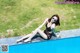 A woman in a black bathing suit sitting on the edge of a swimming pool.