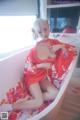 A woman in a red kimono sitting in a bathtub.