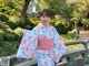 A woman in a pink and blue kimono standing on a bridge.