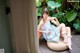 A woman in a blue dress sitting on a wicker chair.