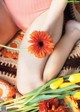 A woman sitting on a rug with a bunch of flowers.