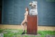 A naked woman standing next to a large metal sculpture.