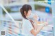 A woman in a white shirt drinking water from a bottle.