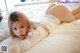 A woman laying on top of a bed in a white shirt.