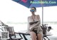 A woman in a bikini sitting at a table under an umbrella.