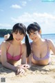 Two young women in bikinis laying on the beach.