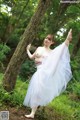 A woman in a white tutu is posing in the woods.