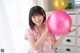 A woman in a pink pajamas holding a pink balloon.