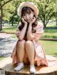 A woman in a pink dress and hat sitting on a tree stump.