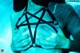 A woman wearing a black bra with a pentagram on it.