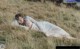 A woman laying in a field of tall grass.