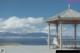 A woman sitting on a bench in front of a gazebo.