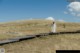 A woman in a white dress walking across a grassy field.