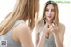 A woman applying lipstick in front of a mirror.