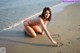 A woman in a bikini writing in the sand on the beach.