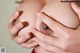 A close up of a woman's breasts with her hands on her breasts.